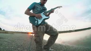 日落时分，一位音乐家吉他手在水边弹奏电吉他。 男吉他手概念